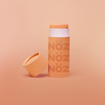 Load image into Gallery viewer, Orange Nöz Sunscreen bottle is standing, the cap is off and it is placed near the bottle.
