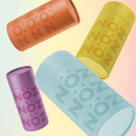 Load image into Gallery viewer, Four Nöz Sunscreen bottles (orange, yellow, purple, and blue) are "falling".
